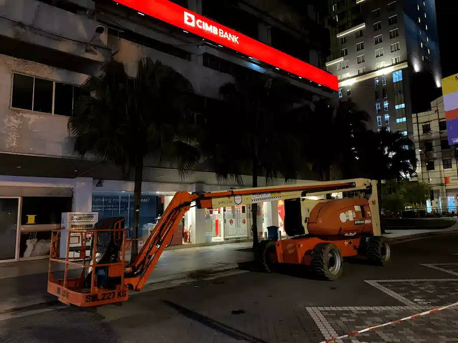 JLG boom lift with lights on, operating at a project site at night