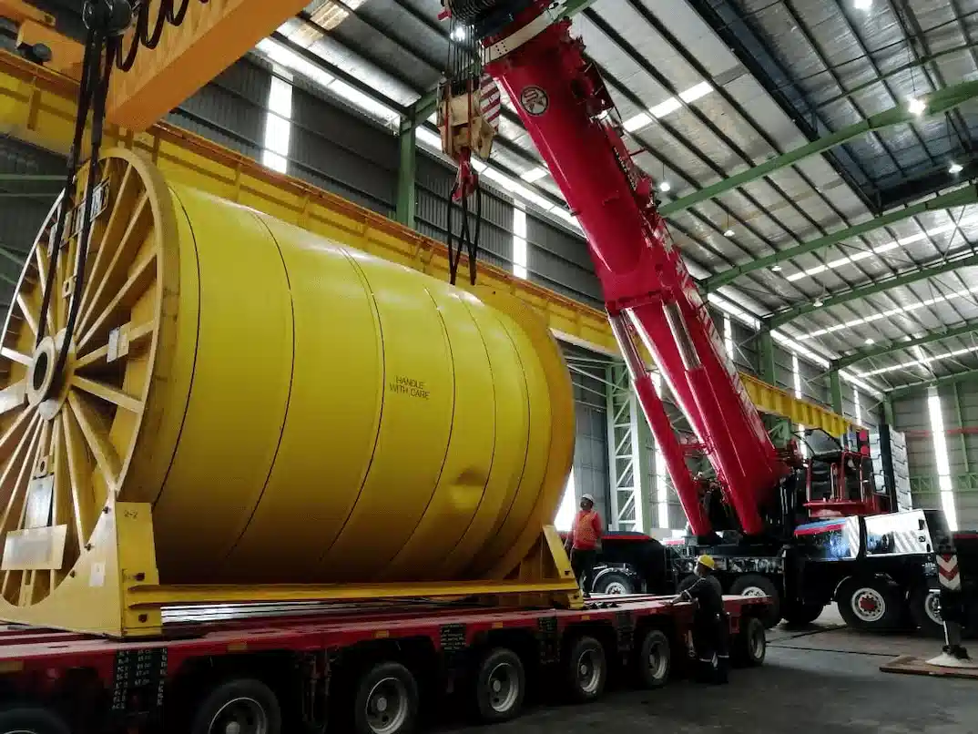 Red mobile crane performing an industrial lift at a worksite in Johor